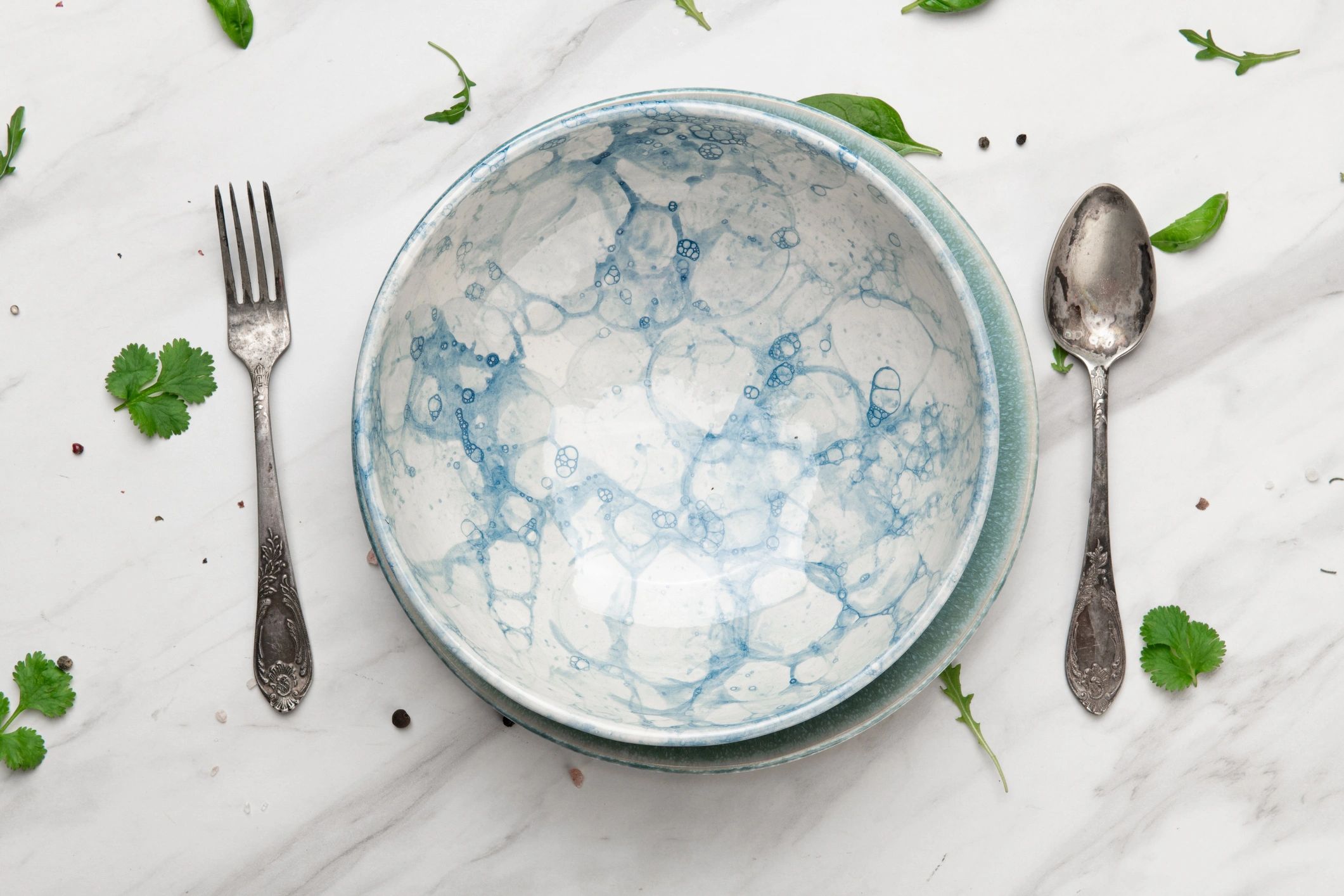 Blue ceramic plate with cutlery and herbs